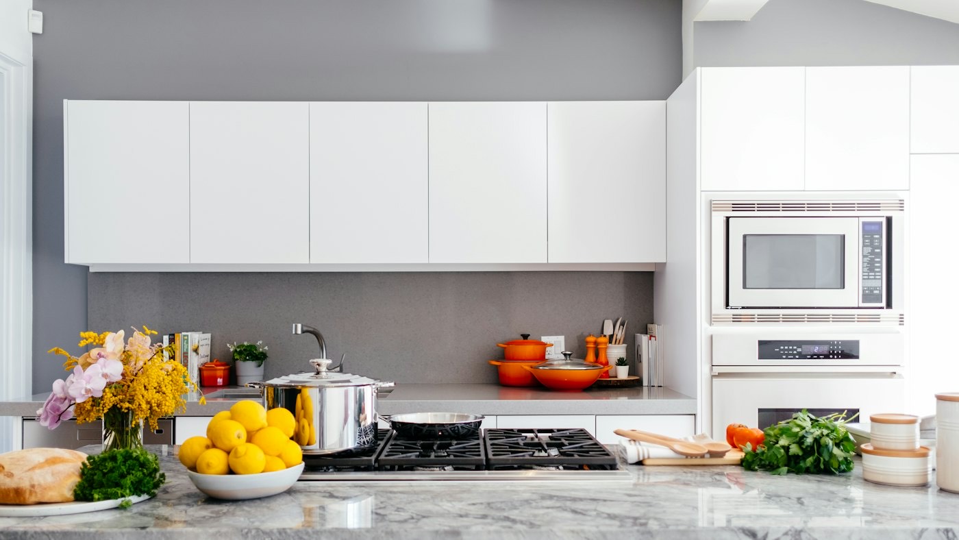 A bright, tidy kitchen with white cabinets, fresh lemons and flowers